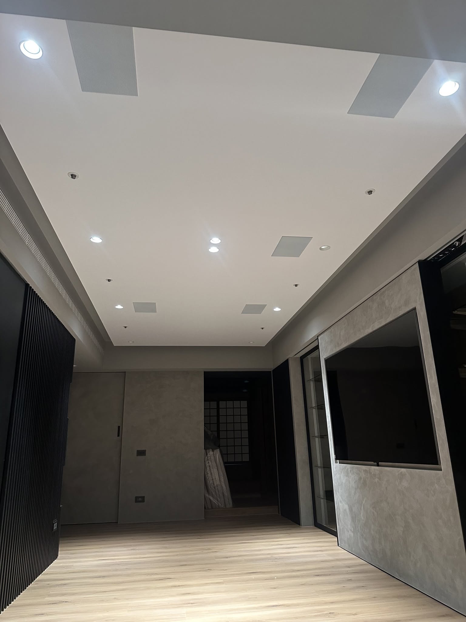 小坪數客廳影音整合完成後全景，天花嵌入喇叭與貼牆電視，簡約沉浸兼具